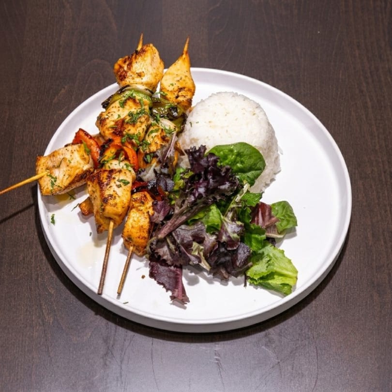 Chicken skewers with bell peppers and onions, served with white rice and a side salad.